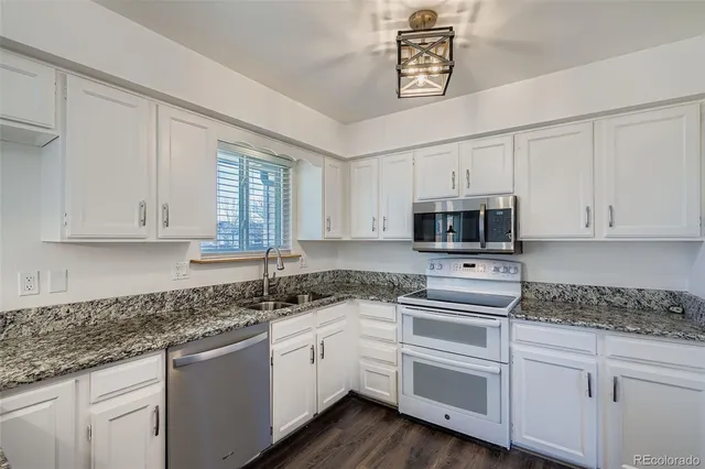a kitchen with stainless steel appliances granite countertop a sink a stove a microwave and cabinets
