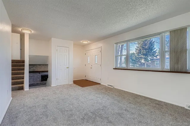a view of an empty room with furniture and a window