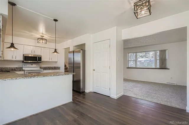 a view of kitchen with granite countertop stainless steel appliances stove refrigerator and a window