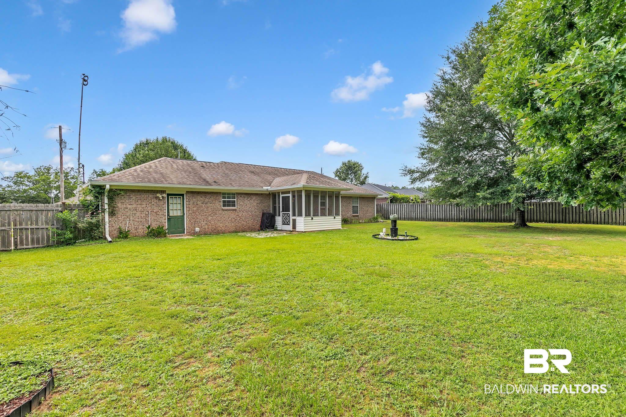 13072 Labradors Run Foley, AL 36535 - Photo 5 of 31 Back of property featuring brick siding, a fenced backyard, and a sunroom