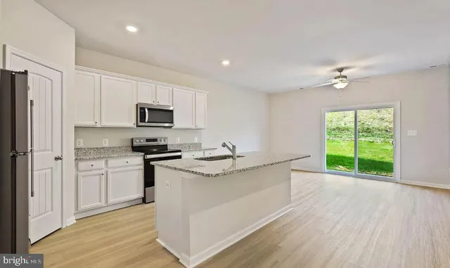 a kitchen with stainless steel appliances granite countertop a sink a stove a refrigerator cabinets and a window