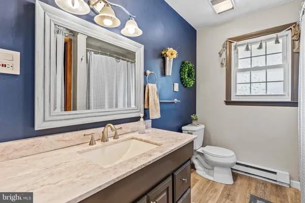 a bathroom with a granite countertop sink toilet and a mirror