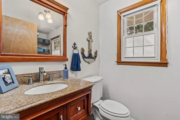 a bathroom with a granite countertop toilet sink and mirror