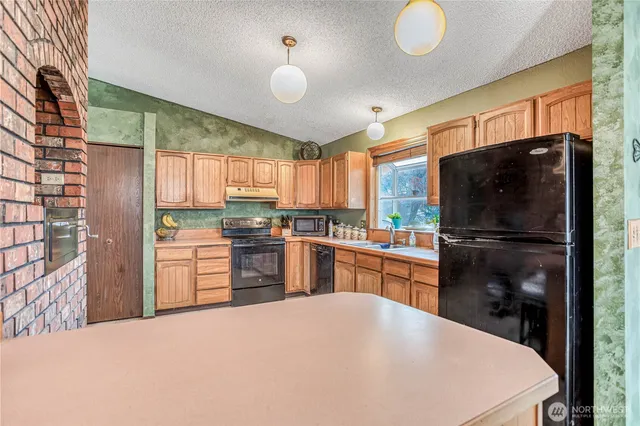 a kitchen with granite countertop a refrigerator stove top oven and sink