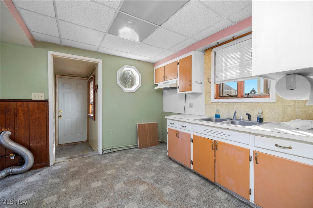 6927 North Wildacre Road Curtice, OH 43412 - Photo 21 of 44 Kitchen featuring light countertops, healthy amount of natural light, a drop ceiling, under cabinet range hood, and light carpet