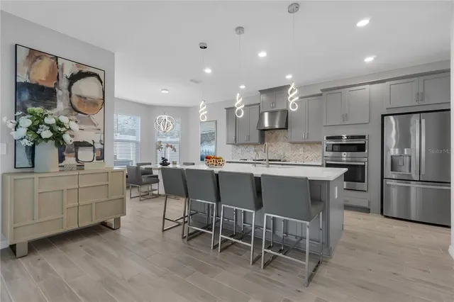 a kitchen with kitchen island granite countertop a refrigerator a stove a sink and white cabinets with wooden floor