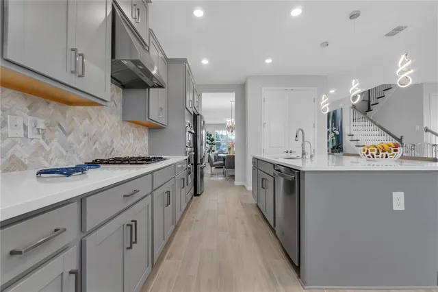 a large kitchen with stainless steel appliances lots of counter space and a sink
