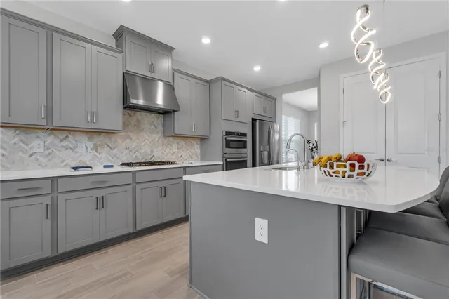 a kitchen with kitchen island granite countertop a sink cabinets and stainless steel appliances