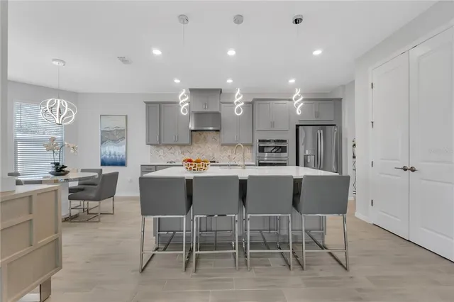 a kitchen with stainless steel appliances kitchen island granite countertop a sink and chairs