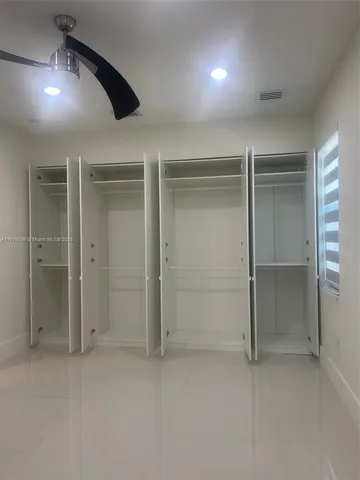 an empty room with closet and a chandelier fan
