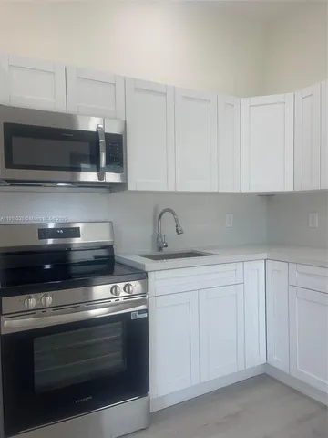 a kitchen with white cabinets and appliances