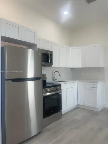 a kitchen with a refrigerator stove and white cabinets