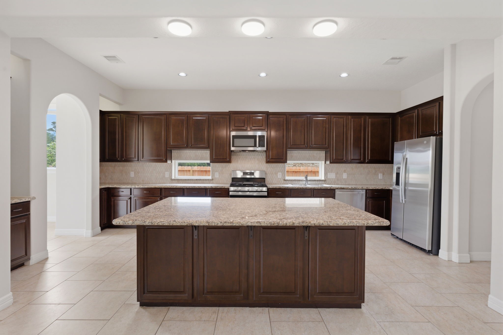 8403 Greenridge Manor Lane Spring, TX 77389 - Photo 12 of 48 Spacious kitchen with wood cabinets, granite countertops, a large island for entertaining, and stainless steel appliances—a chef’s dream.