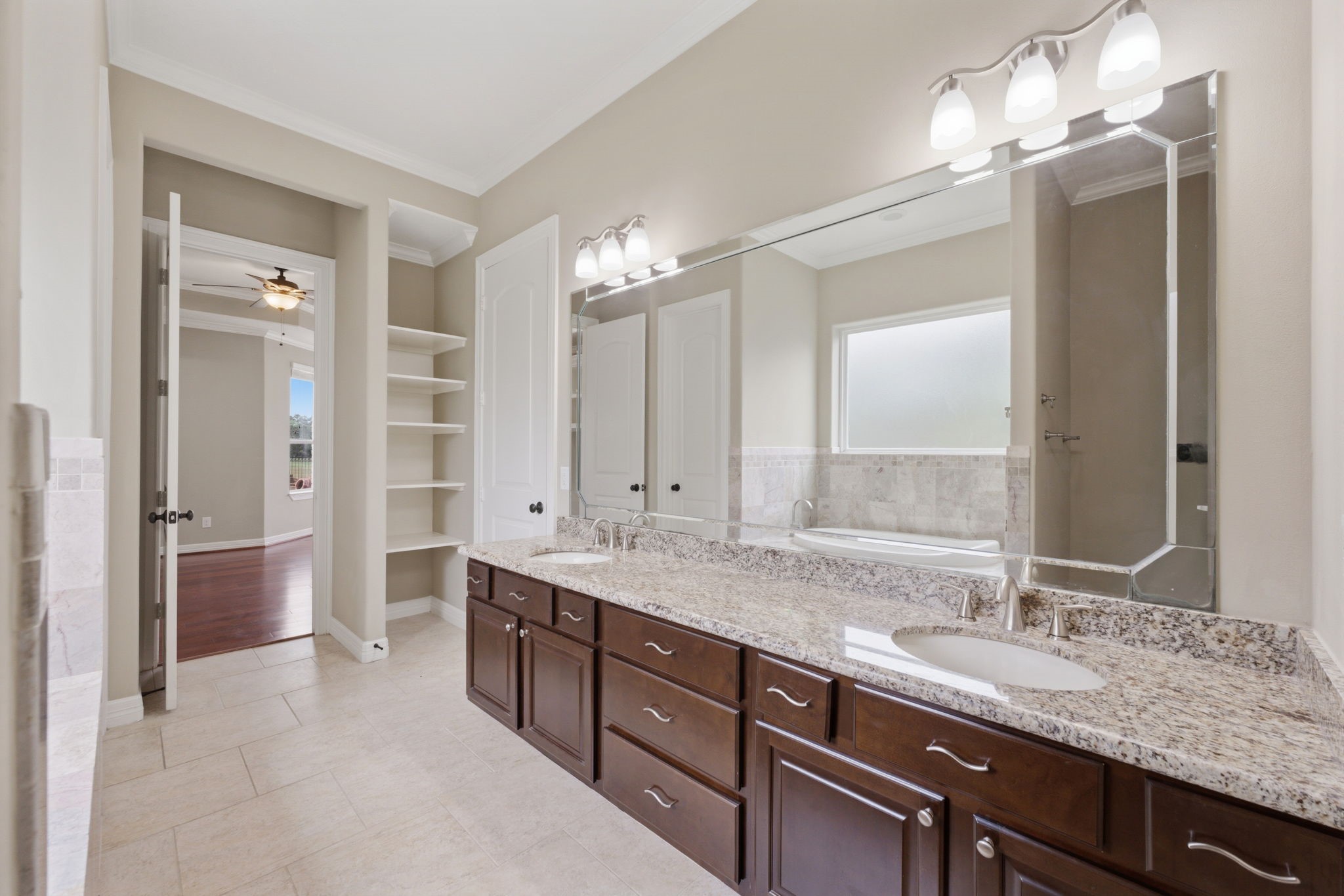 8403 Greenridge Manor Lane Spring, TX 77389 - Photo 20 of 44 Primary bathroom features a spacious double vanity with granite countertops and ample cabinetry. It includes a large mirror, modern lighting, and built-in shelving.