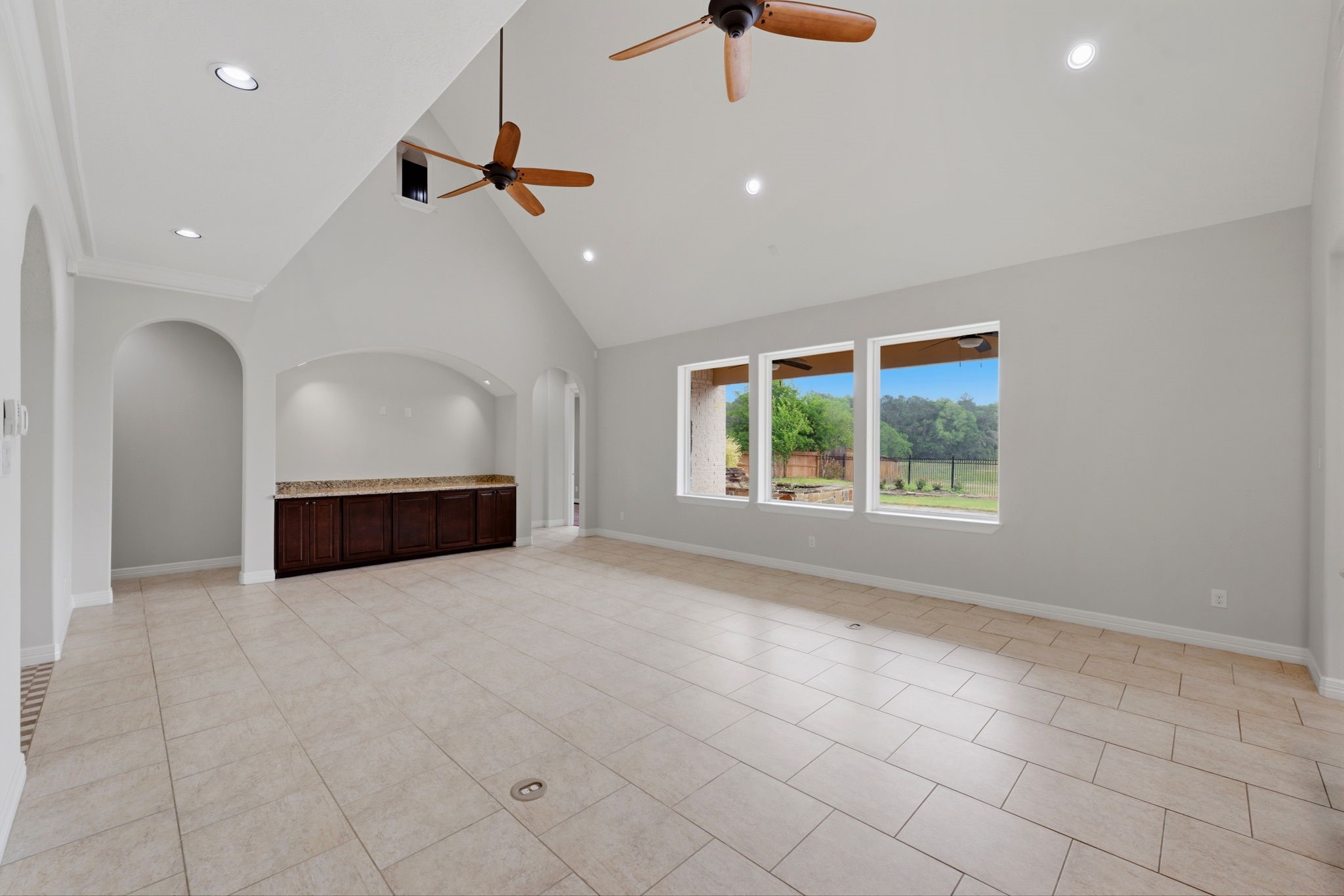 8403 Greenridge Manor Lane Spring, TX 77389 - Photo 7 of 44 This spacious living area features high ceilings with recessed lighting and ceiling fans. Large windows offer abundant natural light and views of the outdoors. The room includes a built-in area with dark wood cabinetry and a granite countertop, perfect for entertaining.