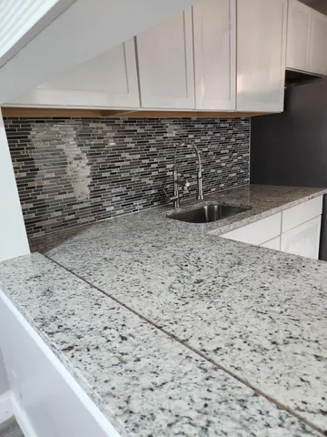 a kitchen with granite countertop white cabinets and a white stove