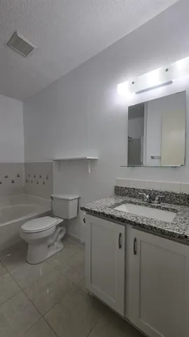 a bathroom with a granite countertop toilet sink and mirror