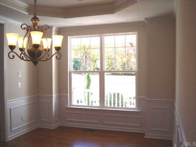 204 Forbes Road Wake Forest, NC 27587 - Photo 2 of 12 Spacious Formal Dining Room with elegant chandelier, tray ceiling, crown molding, chair rail , picture frame molding and beutiful hardwood floors.