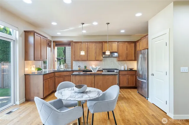 a kitchen with stainless steel appliances granite countertop a kitchen island hardwood floor sink stove dining table and chairs