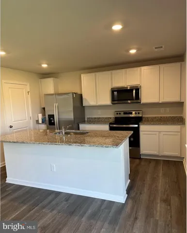 a kitchen with kitchen island granite countertop a sink cabinets and stainless steel appliances