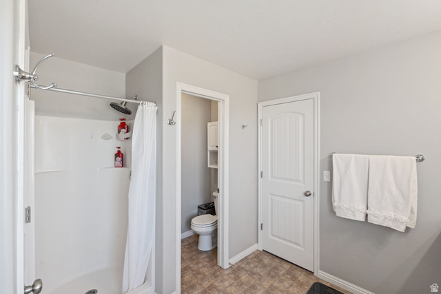 444 South Saddle Road Grantsville, UT 84029 - Photo 14 of 33 Shower enclosure with white surround, rainfall shower head, and an adjacent water closet with built-in shelving