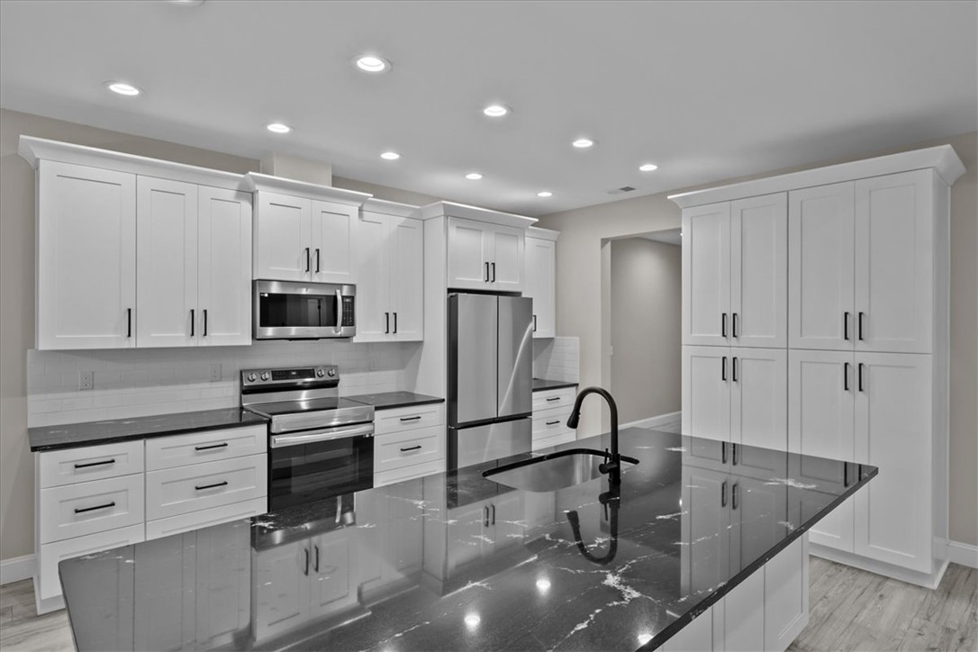 105 Bree Drive Anderson, SC 29621 - Photo 15 of 48 A contemporary kitchen showcasing sleek black granite countertops and integrated stainless steel appliances.
