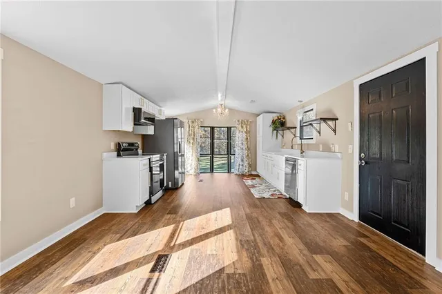 a view of a kitchen with wooden floor electronic appliances and windows