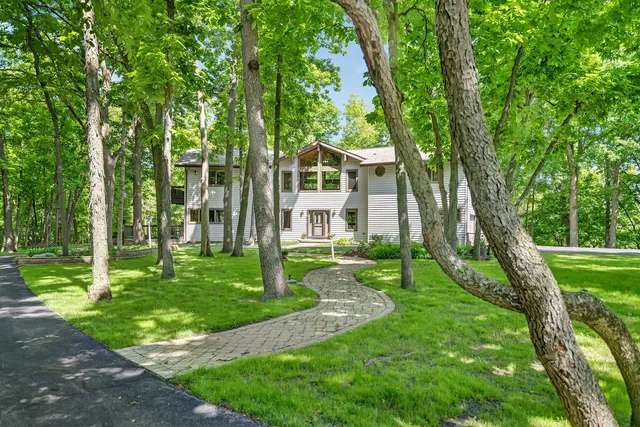 a view of a house with a big yard plants and large trees