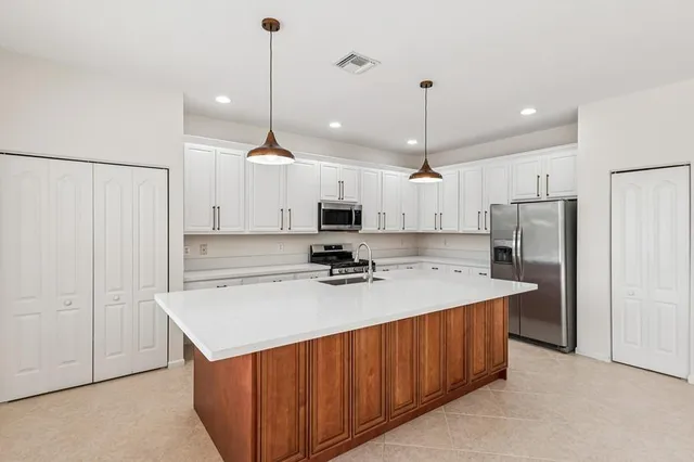 a kitchen with kitchen island a sink stainless steel appliances and refrigerator