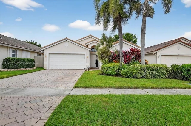 a front view of a house with a garden and trees