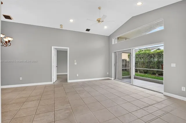 a view of an empty room with kitchen and window