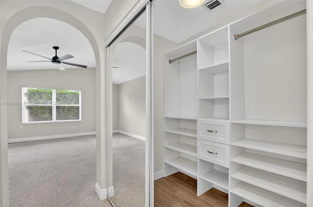 an empty room with a window and ceiling fan