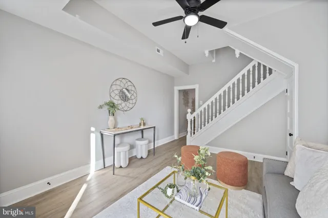 a view of a livingroom with furniture a ceiling fan and wooden floor