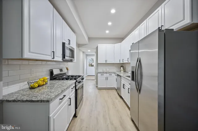 a kitchen with stainless steel appliances granite countertop a refrigerator a stove and a sink