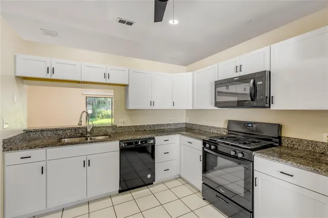 a kitchen with granite countertop a stove sink and cabinets