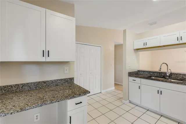 a kitchen with granite countertop white cabinets and a sink