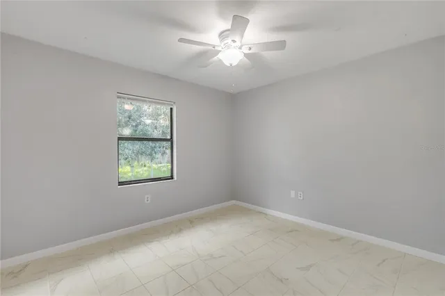 an empty room with windows and fan