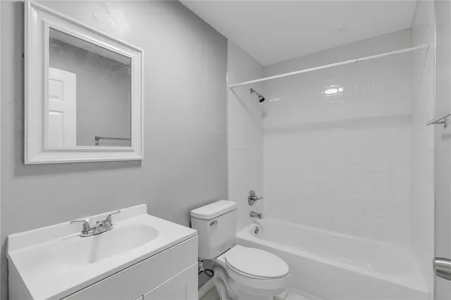 a bathroom with a bathtub shower sink vanity mirror and toilet