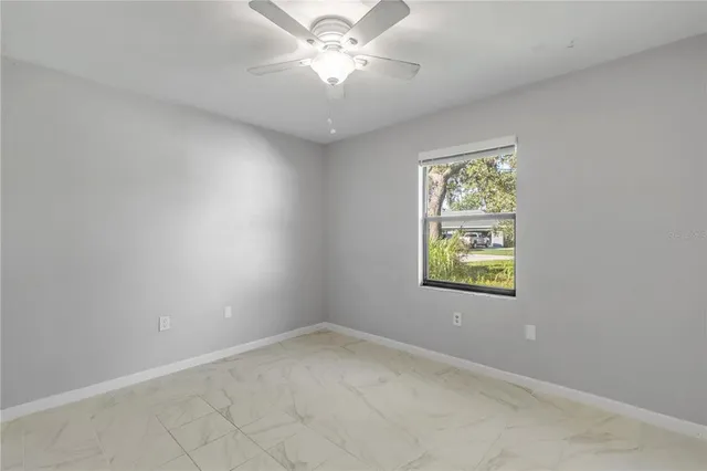 an empty room with windows and ceiling fan