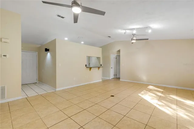 an empty room with kitchen and chandelier fan
