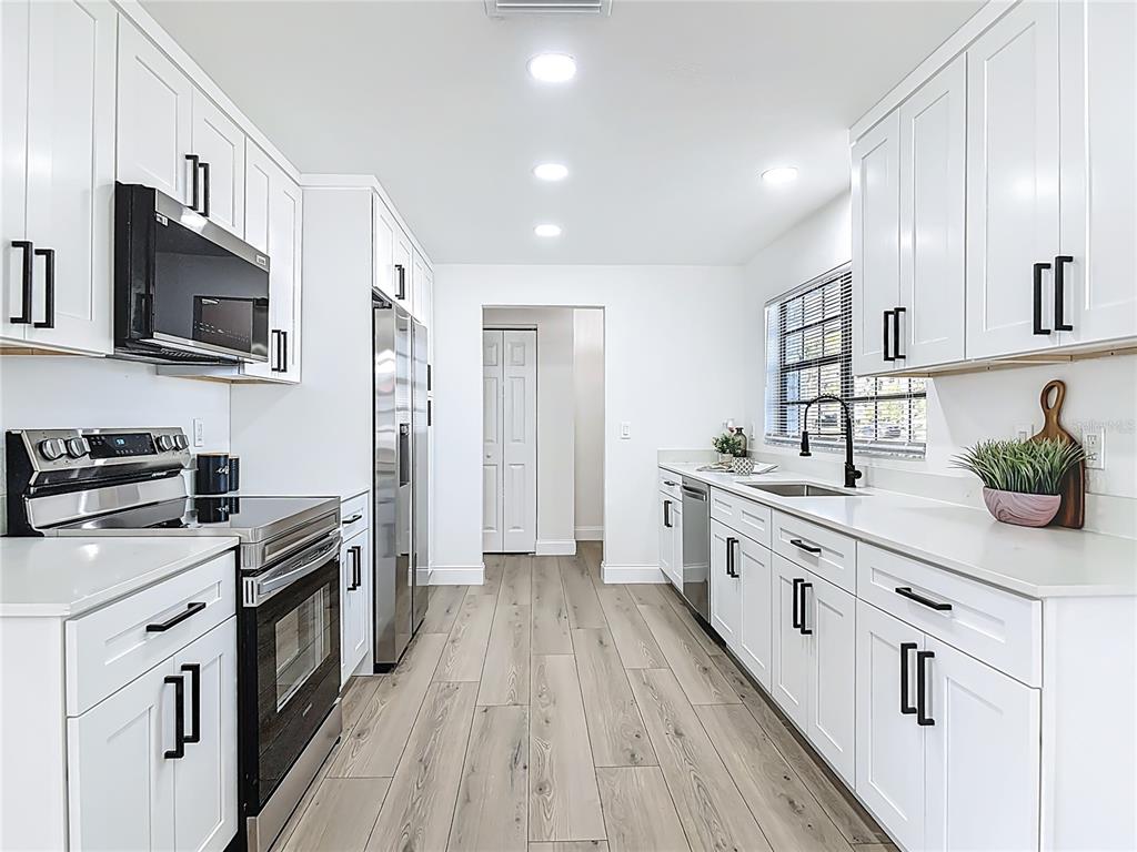 612 Devon Street Port Orange, FL 32127 - Photo 14 of 34 a kitchen with stainless steel appliances a stove top oven a refrigerator a sink and dishwasher with wooden floor
