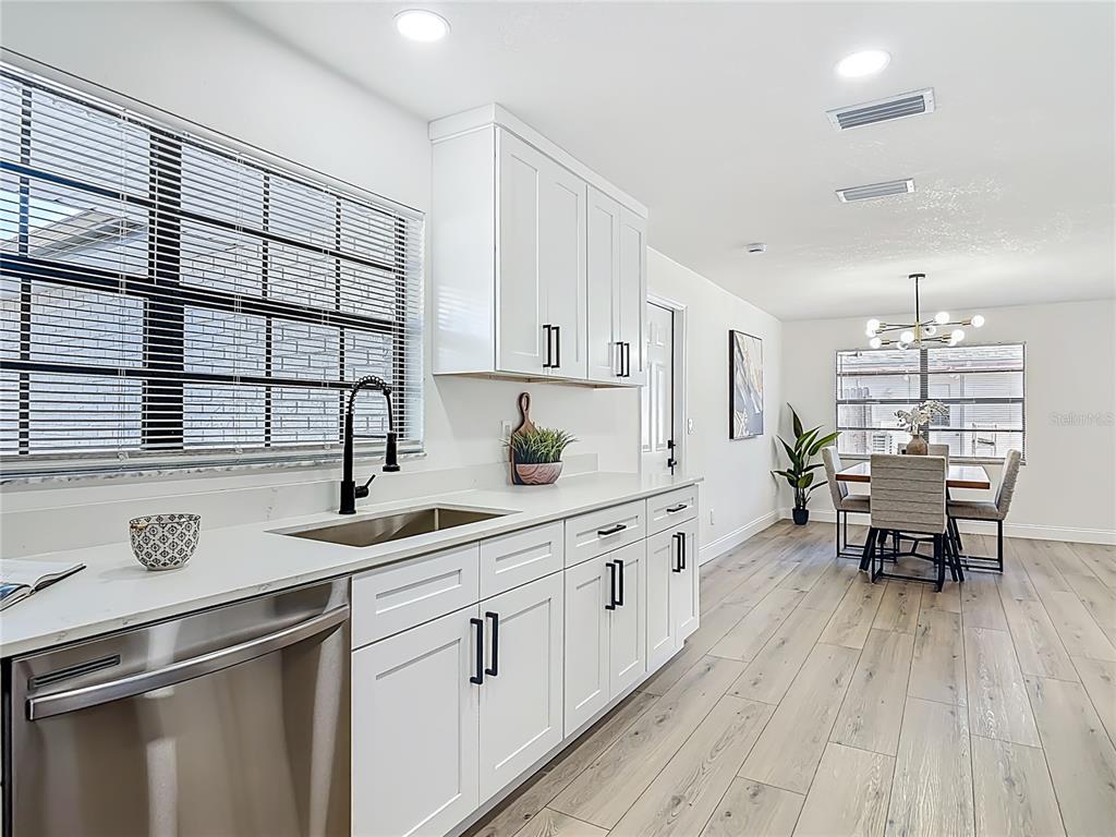 612 Devon Street Port Orange, FL 32127 - Photo 16 of 34 a kitchen with stainless steel appliances granite countertop a stove a sink dishwasher a microwave oven and a dining table with wooden floor