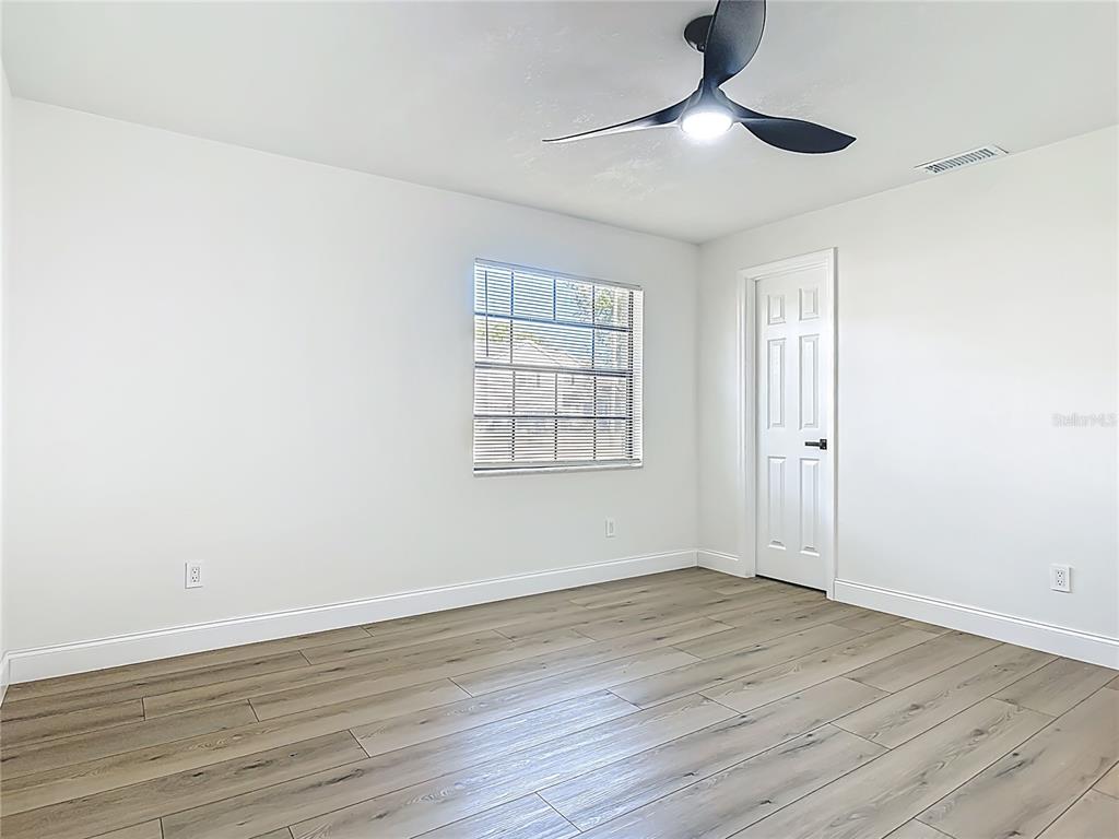 612 Devon Street Port Orange, FL 32127 - Photo 21 of 34 an empty room with wooden floor chandelier fan and windows