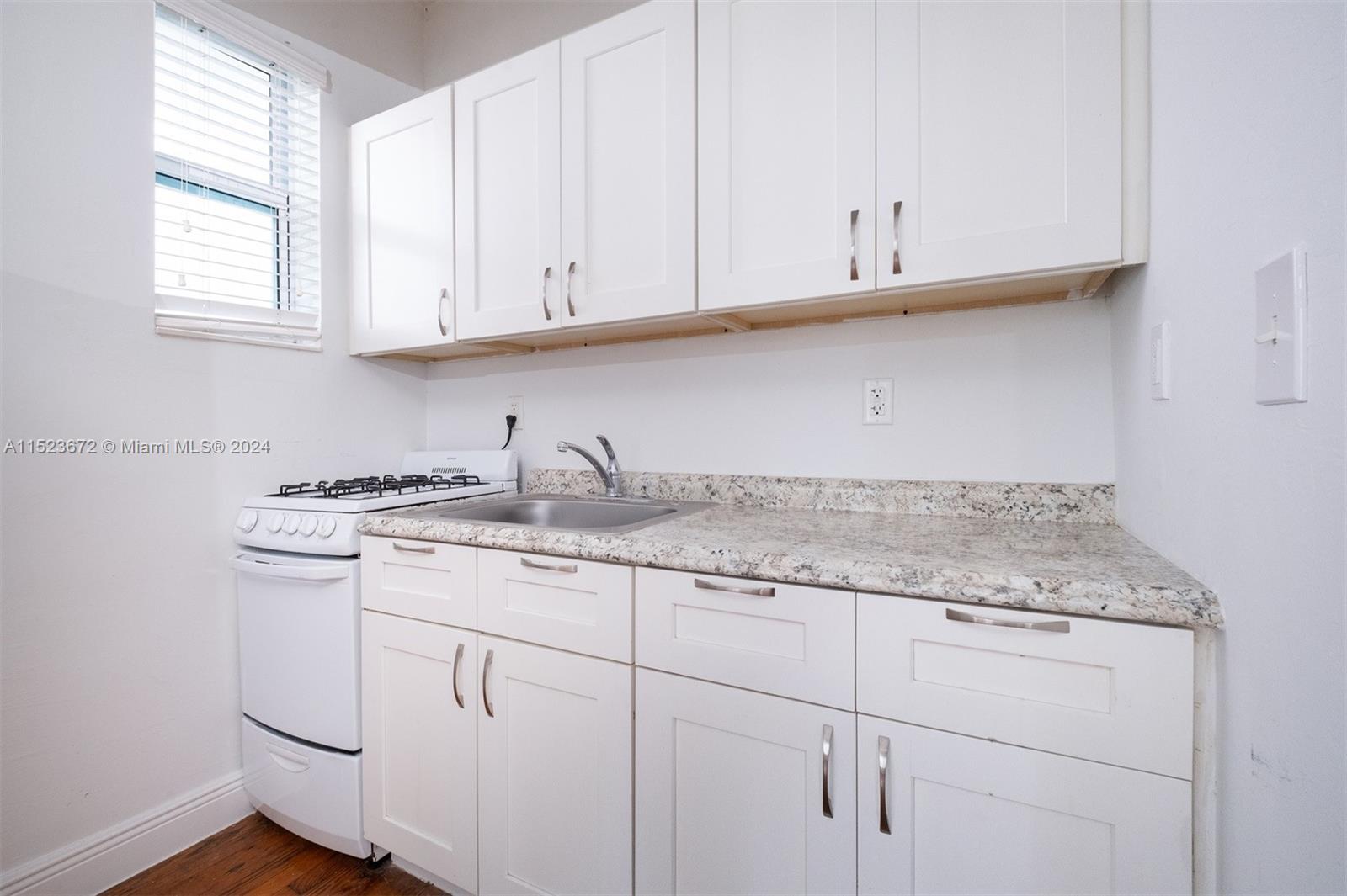 7936 Harding Avenue Miami Beach, FL 33141 - Photo 10 of 18 a kitchen with granite countertop white cabinets and a sink
