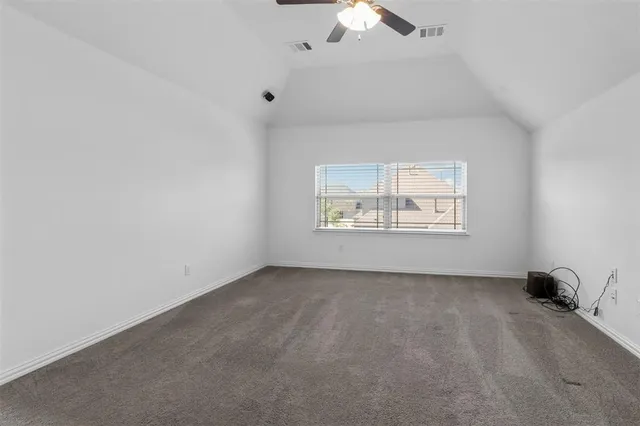an empty room with a chandelier fan and windows