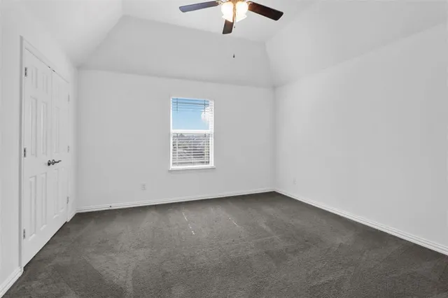 an empty room with a ceiling fan and window