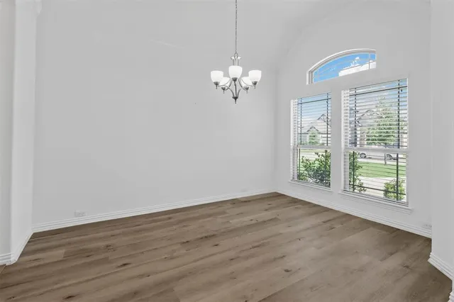a view of a room with wooden floor chandelier and windows