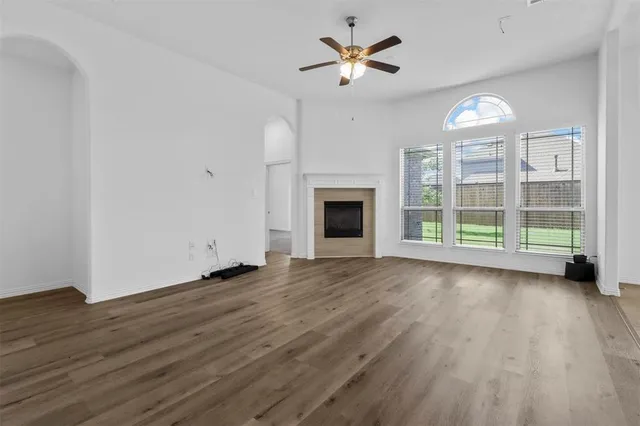 an empty room with wooden floor chandelier and windows