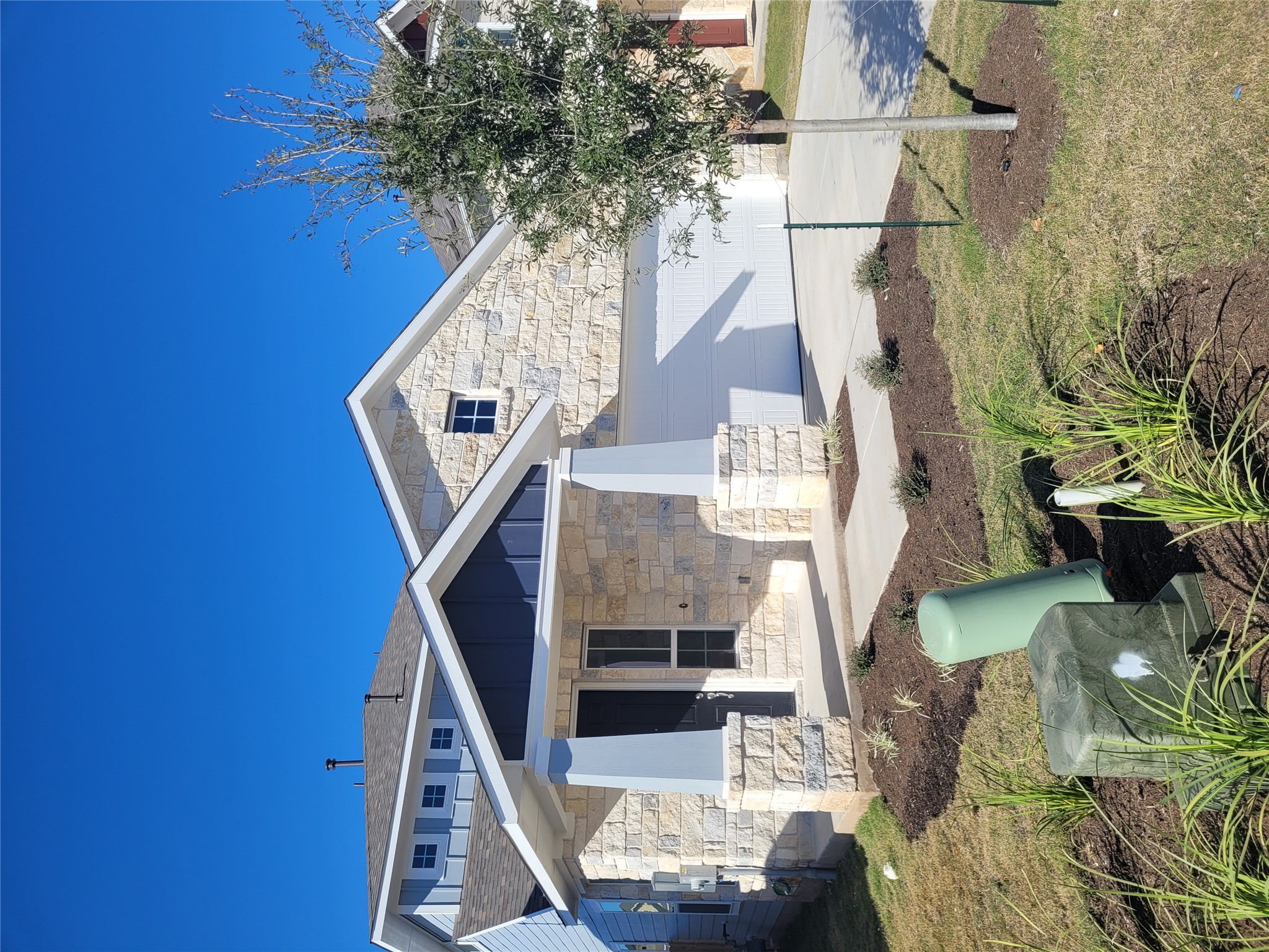 120 Free Stone Drive Georgetown, TX 78628 - Photo 3 of 40 A newly constructed residence showcasing a harmonious blend of light stone and deep blue siding, complemented by a pristine driveway and emerging landscaping.