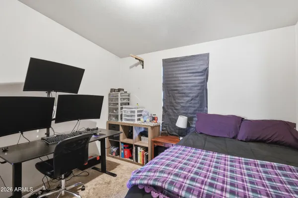 a bedroom with a bed and a computer on a desk